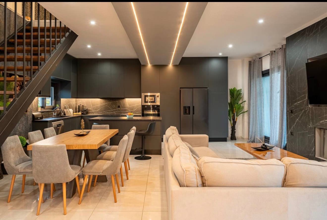 Open-plan kitchen, dining, and living area with dark marble and warm wood accents