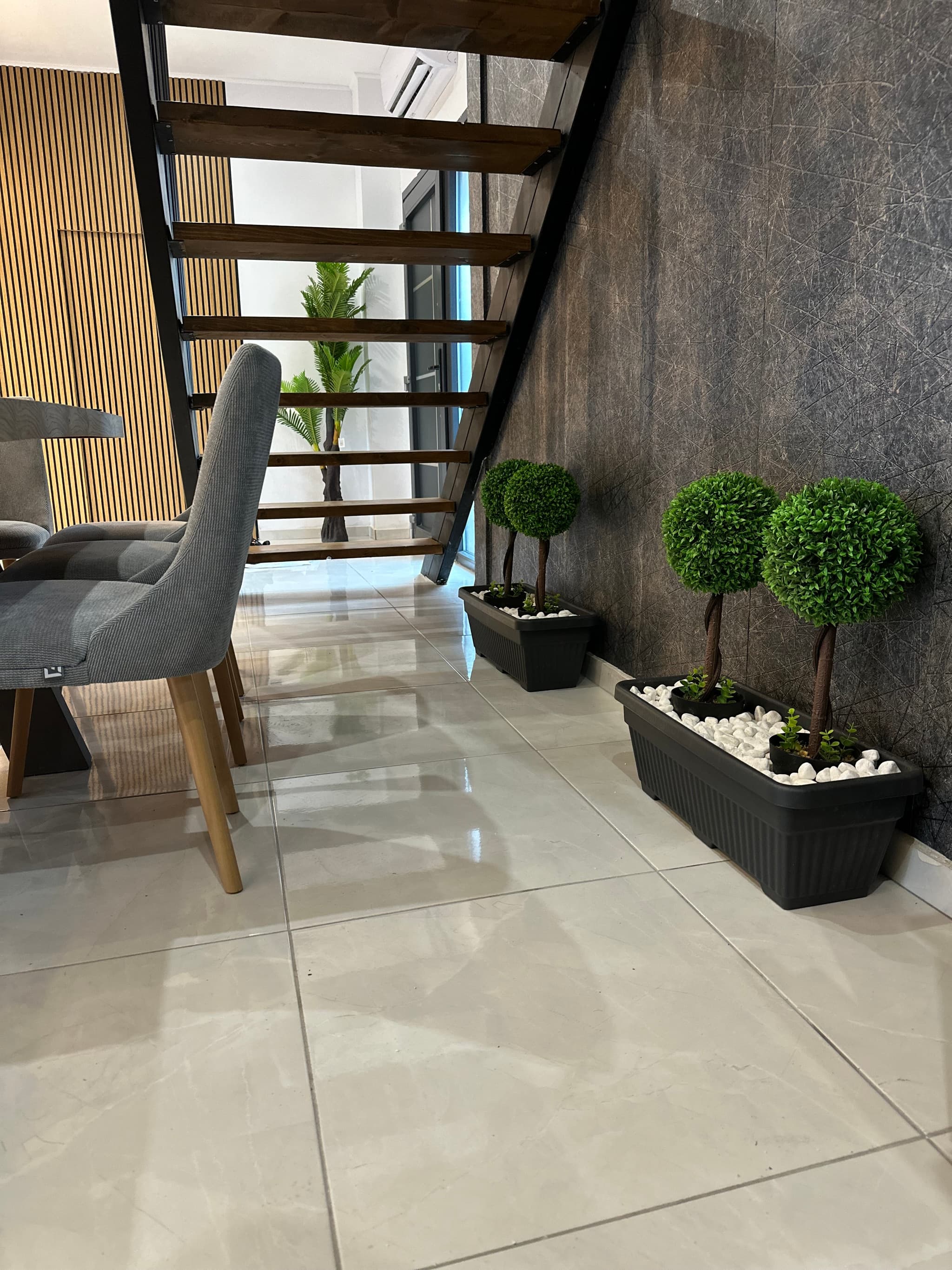 Modern open-tread staircase with wood slat wall and polished floors